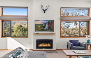 a living room with a fireplace and windows at Lily Chalet in Crackenback