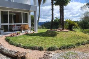 新彼得羅波利斯的住宿－Alto do morro，前面有长凳和棕榈树的房子