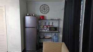 a small kitchen with a refrigerator and a clock on the wall at Fitness Suite in Tijuana
