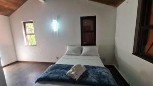 um quarto com uma cama num quarto com duas janelas em Casa Temporada - Petrópolis/RJ em Petrópolis