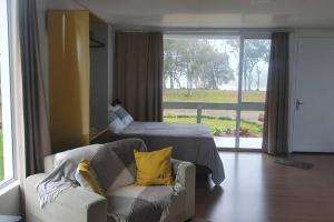 uma sala de estar com um sofá, uma cama e uma janela em Alto do morro em Nova Petrópolis