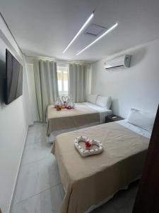 ein Hotelzimmer mit 2 Betten mit Blumen darauf in der Unterkunft Makaiba Residence 003 in Porto De Galinhas