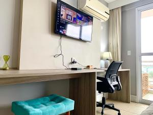 a room with a desk with a chair and a monitor at FLAT exclusivo no Hotel RAMADA Macaé, Smartv, Wifi 512Mbps, piscina e Garagem in Macaé