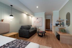 1 dormitorio con cama, sofá y mesa en Hermitage Lodge, en Pokolbin