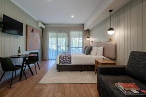 a bedroom with a bed and a couch and a table at Hermitage Lodge in Pokolbin