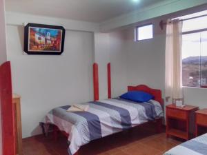 um quarto com uma cama e uma televisão na parede em Casa Tejedora em Chincheros