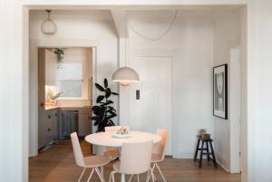 une salle à manger blanche avec une table et des chaises blanches dans l'établissement Poppy's Pad - A Designer Mid century Manly Getaway, à Sydney