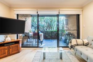 uma sala de estar com uma grande televisão de ecrã plano em Funda Place - Leafy Hideout in Northern Beaches em Sydney