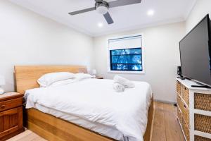 雪梨的住宿－Funda Place - Leafy Hideout in Northern Beaches，一间卧室配有一张床和一台平面电视