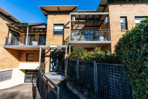 ein Apartmenthaus mit Balkonen und einem Zaun in der Unterkunft Funda Place - Leafy Hideout in Northern Beaches in Sydney