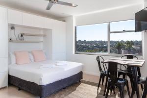 a bedroom with a bed and a table and a window at Mosman Bay Magic - Harbourview Studio with Rooftop in Sydney