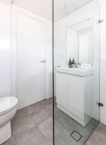 a white bathroom with a toilet and a sink at Mosman Bay Magic - Harbourview Studio with Rooftop in Sydney