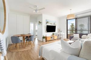 uma sala de estar com um sofá e uma mesa em Fine Pine - Beachside Lifestyle with Two Balconies em Sydney