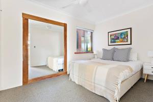 a bedroom with a bed and a large mirror at The Little Manly - Laidback Waterfront Magic in Sydney