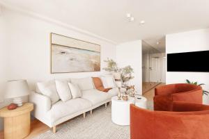 a living room with a white couch and a tv at Harbour Bliss - Exquisite Design, Breathtaking Views in Sydney