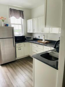 a kitchen with white cabinets and a black counter top at NY3182-9 Private Office w Double SofaBed Keypad in Unionport