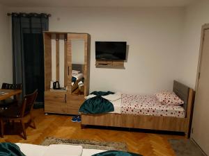 Madigan's Hotel في Kosovo Polje: غرفة نوم مع سرير وتلفزيون على الحائط