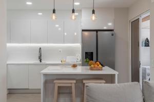 a white kitchen with a table with a bowl of fruit at In the touristic area and with a balcony Casa Branca VI in Funchal