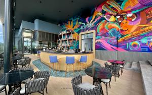 a restaurant with tables and chairs and a colorful wall at Mercure Miri City Centre in Miri