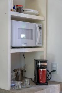 a kitchen counter with a microwave and a coffee pot at Suítes Casa Kamayurá in Trancoso