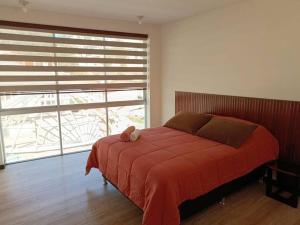 Un dormitorio con una cama roja con un osito de peluche. en Hermoso Dpto. con ubicación excepcional(cala coto) en La Paz
