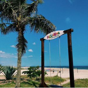 a swing on the beach next to a palm tree at Pousada da Drica in Saquarema