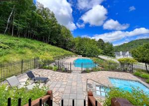 un patio con piscina y valla en Condo moderne, escapade vacance, vue sur montagnes, en Mont-Tremblant