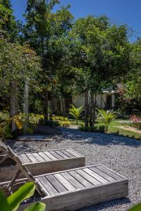 a garden with three wooden steps and trees at Suítes Casa Kamayurá in Trancoso