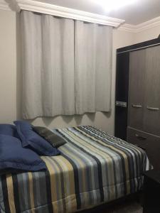 布盧梅瑙的住宿－Quarto para Casal Blumenau，一间卧室配有一张带蓝色枕头的床和一扇窗户。