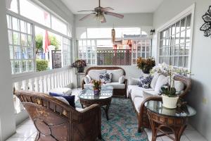 a screened in porch with furniture and windows at Airport Inn in Piarco