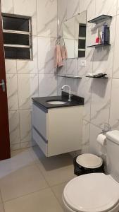 a white bathroom with a sink and a toilet at Cleyton Morada in Curitiba