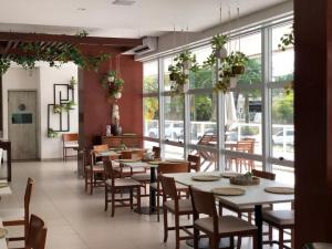 un ristorante con tavoli, sedie e finestre di O MELHOR Resort em Riviera São Lourenço 500m da praia de Riviera, com SPA, piscinas aquecidas externa e interna, cinema, restaurantes e bar! MÓDULO 8 a Bertioga