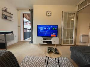 a living room with a tv and a table at Coventry City Centre 2 Bed 2 Bath Apartment With FREE Secured Parking, Balcony, PS4 - Reverie Stays in Coventry