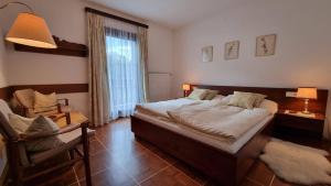 ein Schlafzimmer mit einem Bett, einem Stuhl und einem Fenster in der Unterkunft Pension Hattinger in Maria Alm am Steinernen Meer