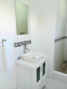 ein weißes Badezimmer mit einem Waschbecken und einem Spiegel in der Unterkunft Serenity Seaview Suite in Anse La Raye