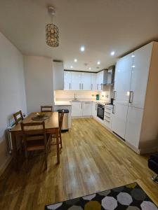 a kitchen with a wooden table and a kitchen with white cabinets at Wembley Stadium Luxurious Apartment in London