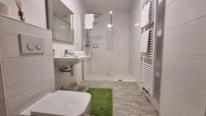 a white bathroom with a toilet and a sink at Pension Hattinger in Maria Alm am Steinernen Meer