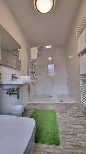 ein Badezimmer mit einem grünen Teppich, einem Waschbecken und einer Dusche in der Unterkunft Pension Hattinger in Maria Alm am Steinernen Meer