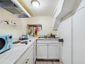 a kitchen with white cabinets and a sink and a microwave at Pine Forest Zen Cottage - 10 min to Fort Bragg in Fayetteville