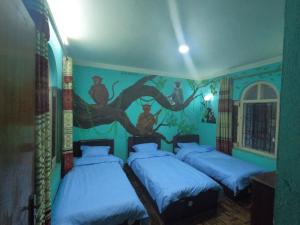 - 3 lits dans une chambre avec un tableau mural dans l'établissement Hello KTM Hostel, à Katmandou