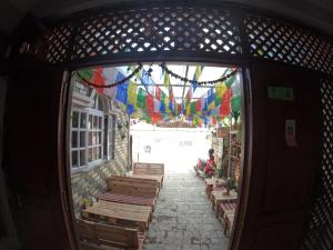 una entrada a un edificio con banderas coloridas y bancos de madera en Hello KTM Hostel en Katmandú