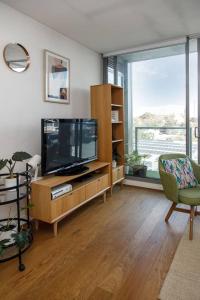 a living room with a tv and a large window at Eden of Abbotsford - A Serene Escape off Johnston St in Melbourne