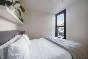 a white bedroom with a bed and a window at Eden of Abbotsford - A Serene Escape off Johnston St in Melbourne