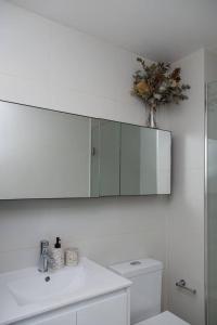 Baño blanco con lavabo y espejo en Eden of Abbotsford - A Serene Escape off Johnston St, en Melbourne