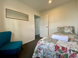 a bedroom with a bed and a blue chair at Alpine Views and River Tracks in Twizel