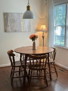 a dining room table with chairs and a vase with flowers at The Mirror Lake Suite in Fayetteville