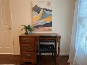 a desk with a potted plant and a painting on the wall at The Mirror Lake Suite in Fayetteville