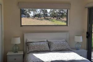 a bedroom with a bed with a window above it at Private Getaway Close to Clifton Beach in Hobart