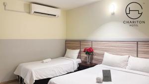 una habitación de hotel con 2 camas y un jarrón de flores en Chariton Hotel Skudai Kiri, en Johor Bahru