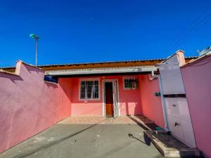 una casa roja y rosa con puerta en Casa na Praia de Guaratiba - Maricá en Maricá